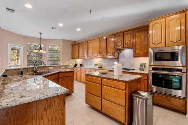 a kitchen with stainless steel appliances granite countertop a sink stove microwave and refrigerator