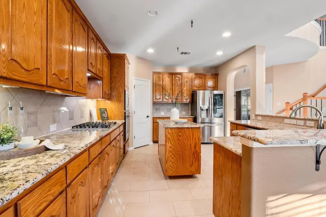 a kitchen with stainless steel appliances granite countertop a sink a stove and a refrigerator