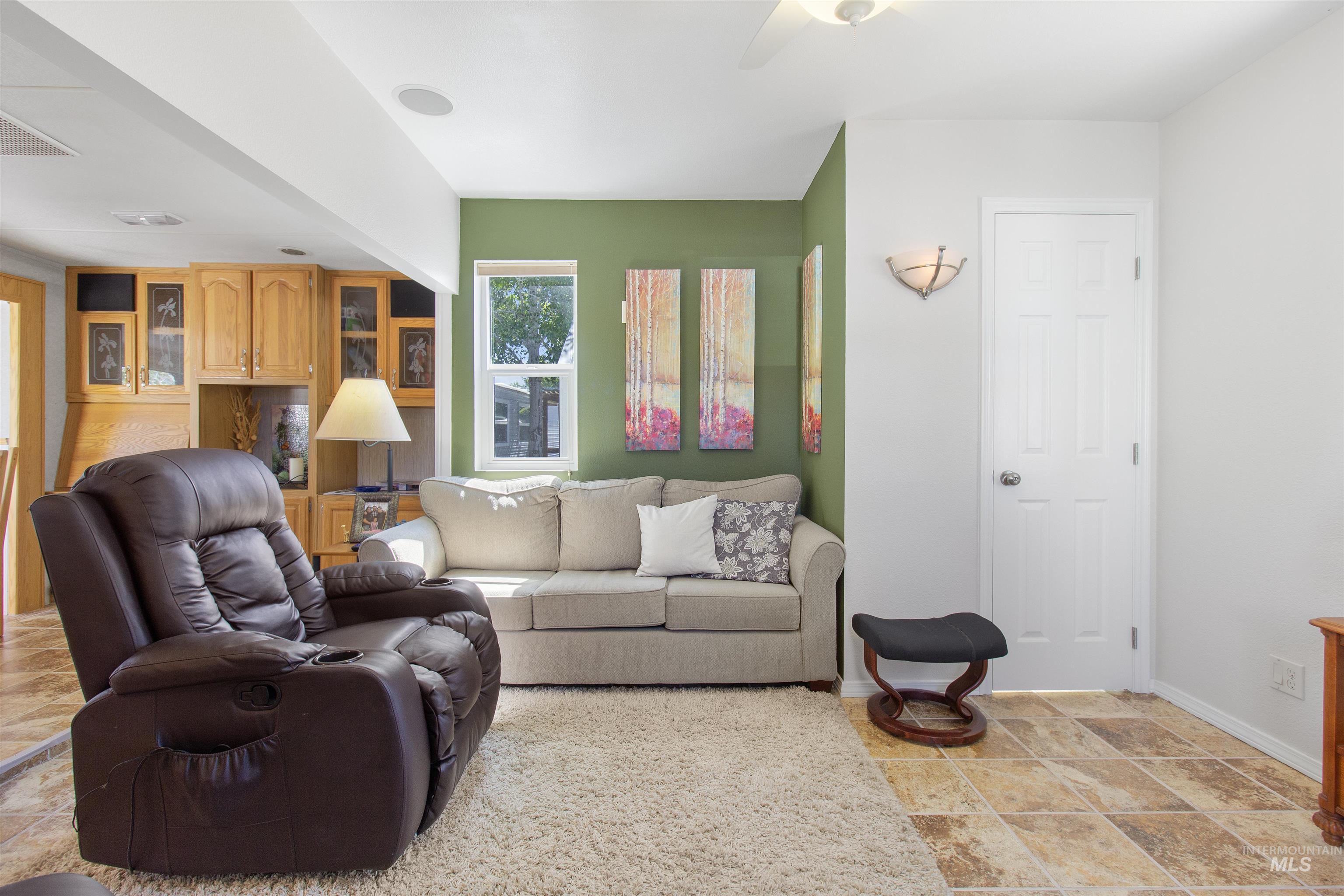 106 West Magic Road Shoshone, ID 83352 - Photo 8 of 45 Living area featuring tile flooring, a built-in wood cabinet with glass door accents, a white paneled door, and a wall-mounted light fixture