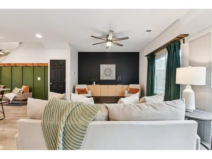 a living room with furniture a large window and a chandelier