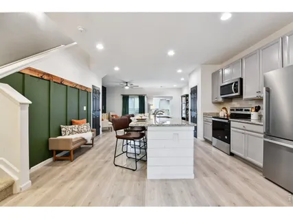a living room with stainless steel appliances furniture and a wooden floor