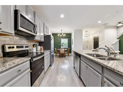 a kitchen with stainless steel appliances granite countertop a sink dishwasher stove top oven and cabinets with wooden floor