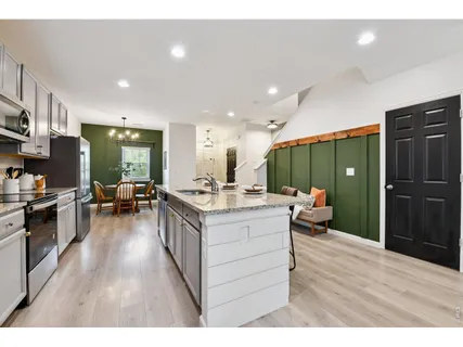 a kitchen with stainless steel appliances kitchen island granite countertop a refrigerator a sink dishwasher a stove and a refrigerator with wooden floor