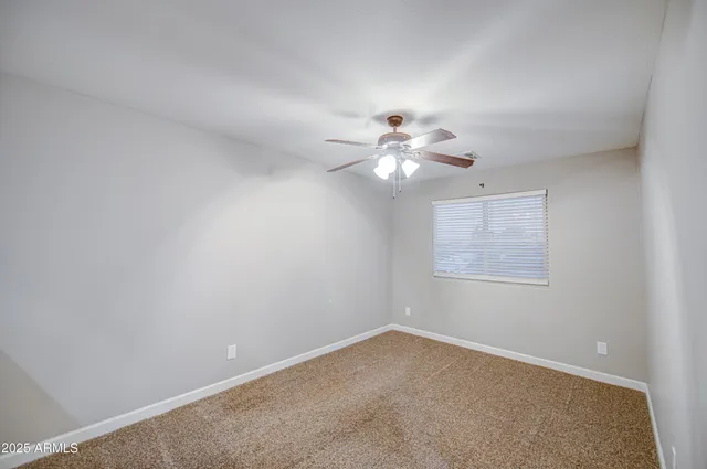 an empty room with windows and ceiling fan