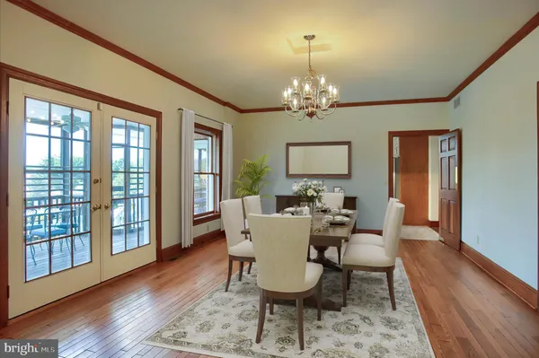 a dining room with wooden floor a chandelier a wooden table and chairs
