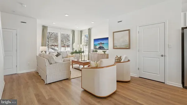 a living room with stainless steel appliances kitchen island hardwood floor and a sink