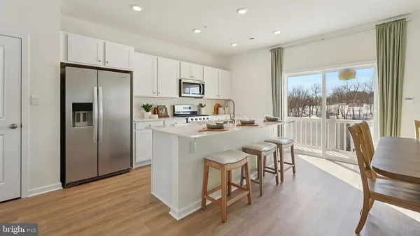 a kitchen with stainless steel appliances granite countertop a refrigerator a stove top oven a sink with island and chairs