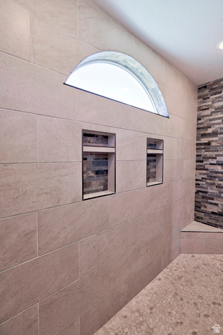 3311 West Allard Summit, UT 84772 - Photo 43 of 97 Tiled shower with a semi-circular transom window, two built-in recessed niches with accent tile, a pebble-stone floor, and a tiled bench