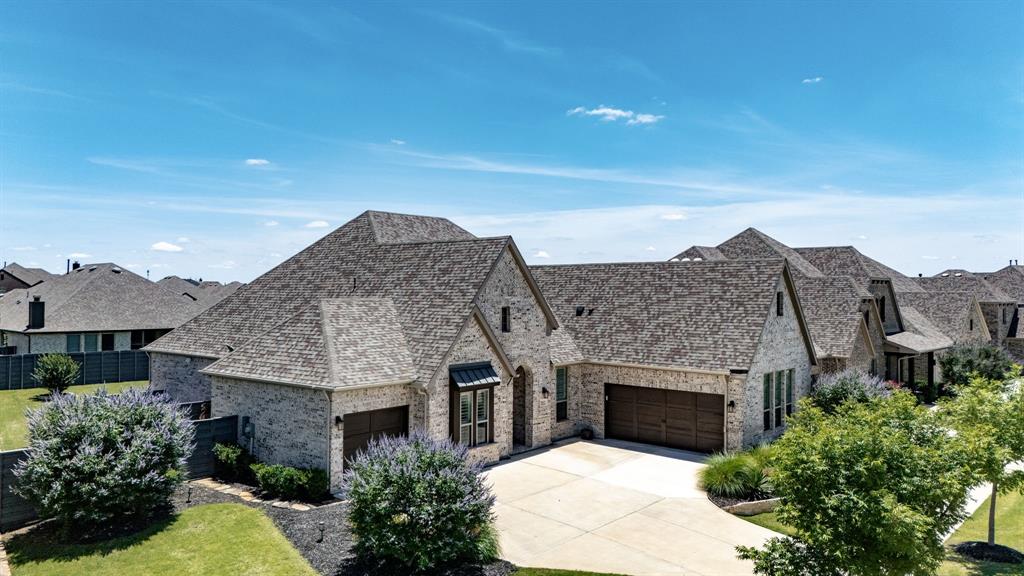 7032 Lookout Lane Little Elm, TX 76227 - Photo 1 of 38 French country style house featuring an attached garage, driveway, brick siding, roof with shingles, and a residential view