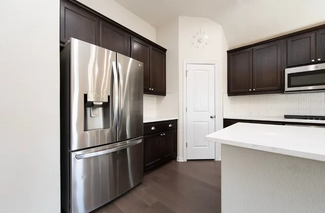 a kitchen with stainless steel appliances kitchen island a refrigerator sink and microwave
