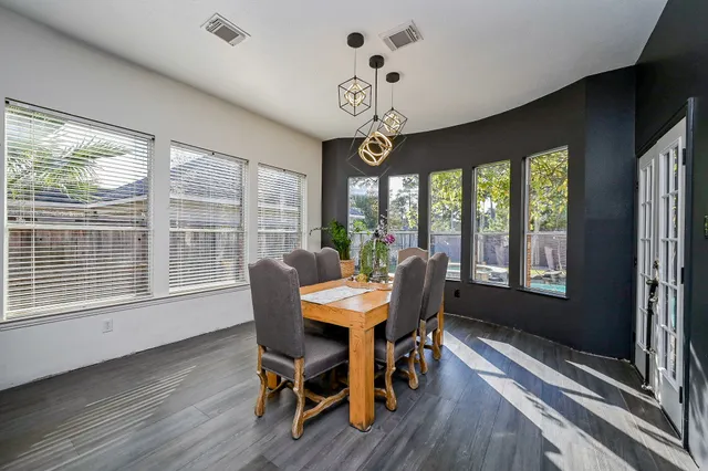 a dining room with wooden floor a chandelier a wooden table and chairs