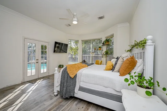a bedroom with a bed and dresser with wooden floor