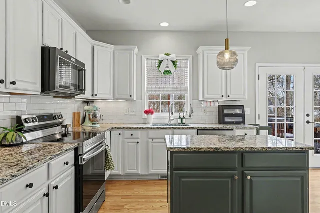 a kitchen with stainless steel appliances granite countertop a sink a stove cabinets and a wooden floor