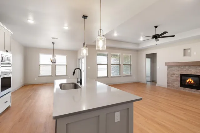 a kitchen with a sink a fireplace and wooden floor