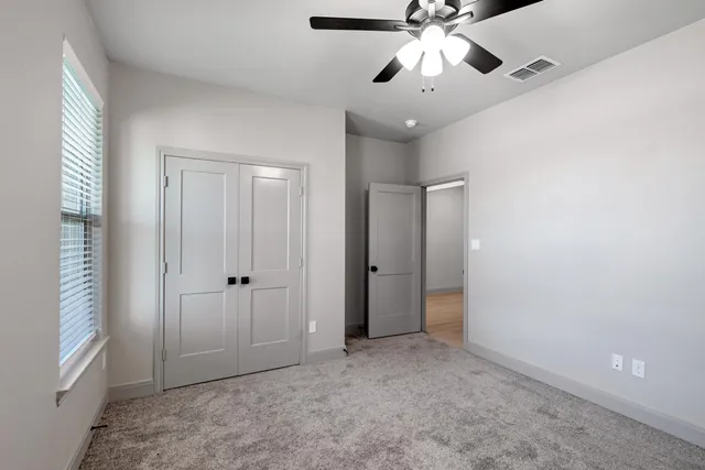 a view of an empty room and chandelier fan