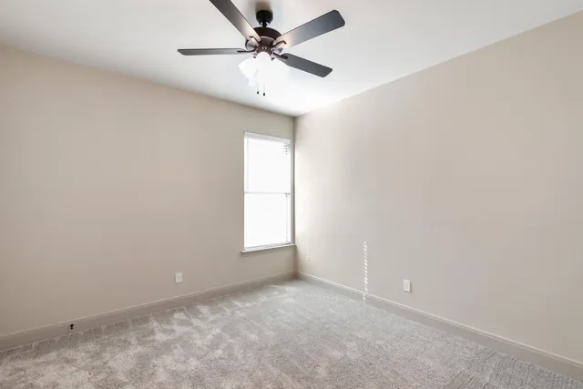 an empty room with a window and a fan