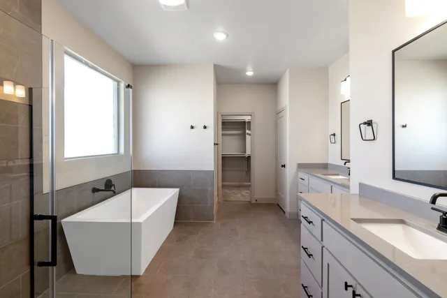 a bathroom with a tub sink double vanity granite tub shower and mirror