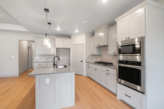 a kitchen with stainless steel appliances granite countertop a sink stove microwave and refrigerator