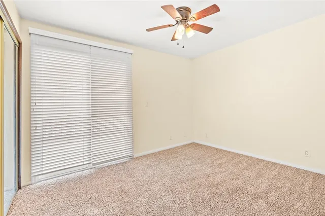 an empty room with a window and a fan