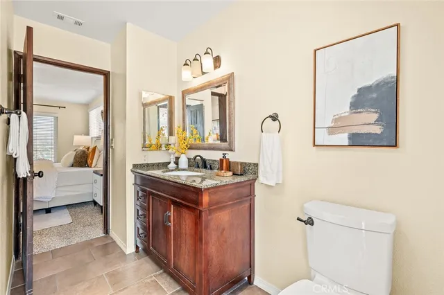 a spacious bathroom with a granite countertop sink a toilet and a mirror