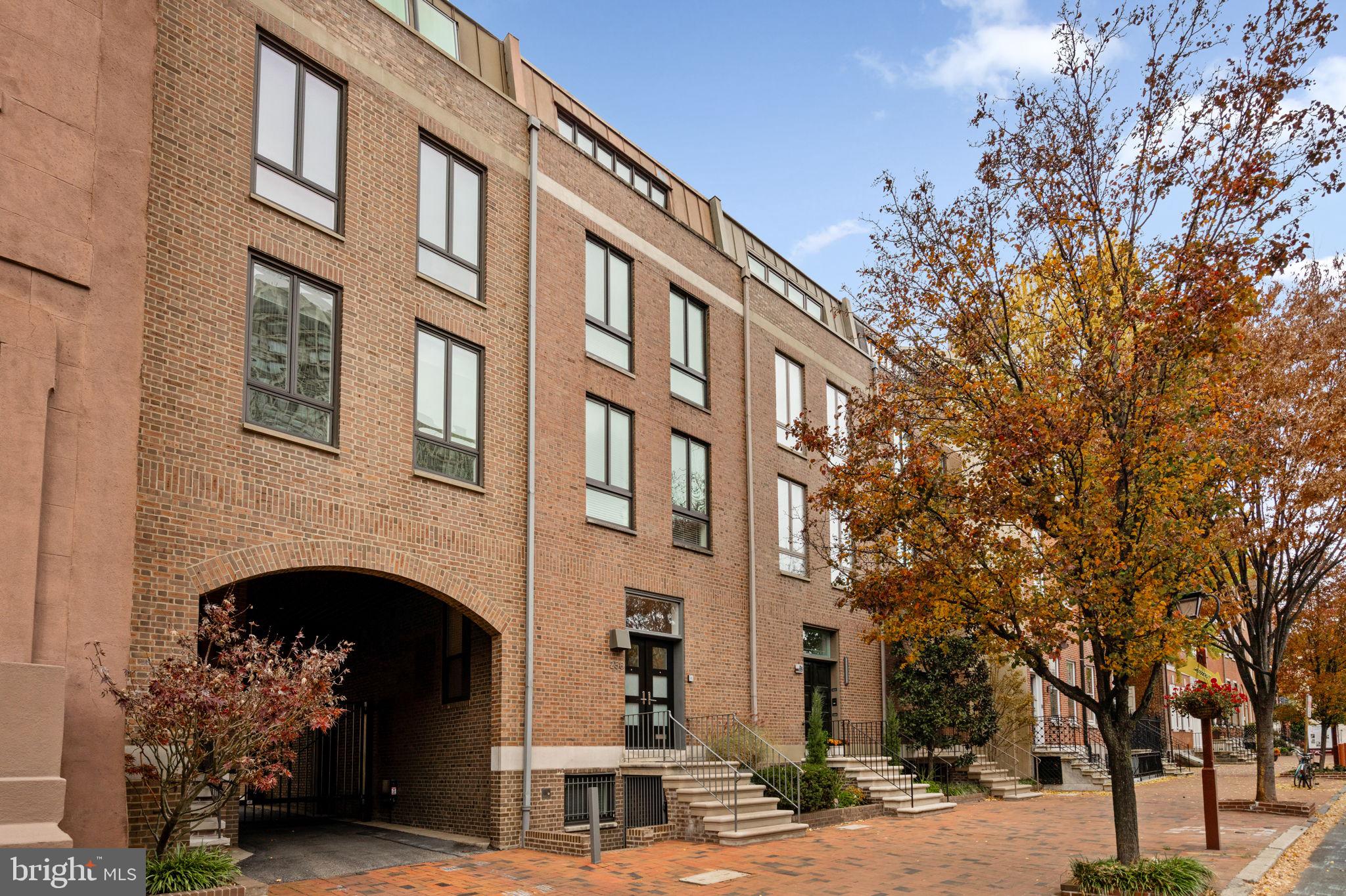 a front view of a building with garden and trees