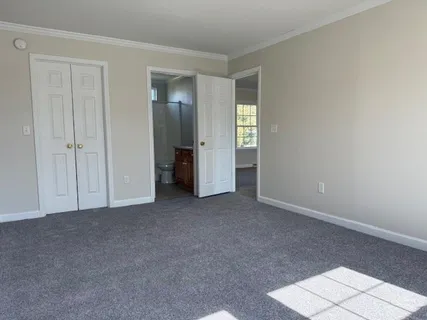 a view of an empty room with closet and a window