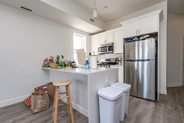 a kitchen with stainless steel appliances granite countertop a refrigerator a sink dishwasher a oven with white cabinets and wooden floor