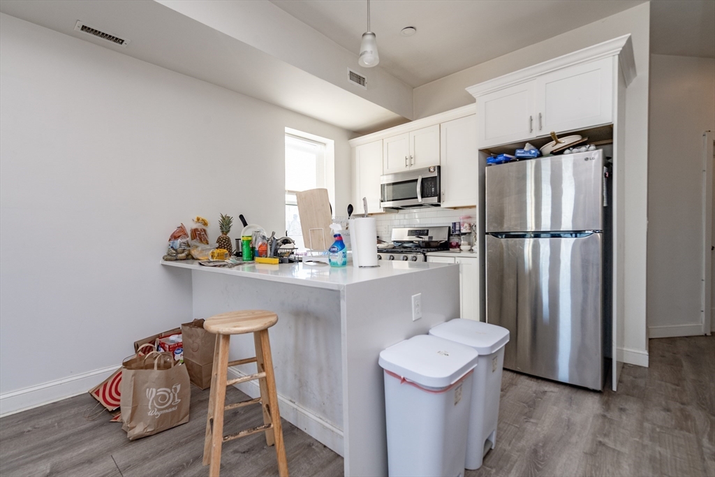 301-305 Dudley Street Boston, MA 02119 - Photo 7 of 14 a kitchen with stainless steel appliances granite countertop a refrigerator a sink dishwasher a oven with white cabinets and wooden floor