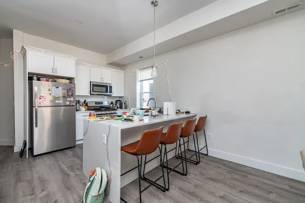 a kitchen with stainless steel appliances a dining table chairs refrigerator and sink