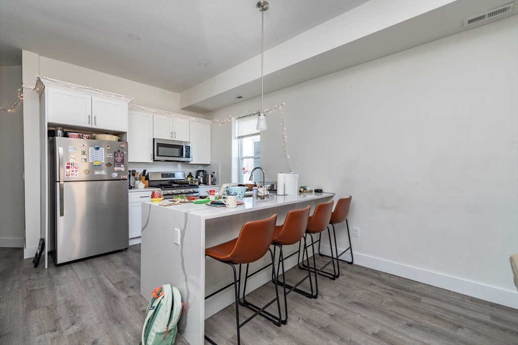 301-305 Dudley Street Boston, MA 02119 - Photo 8 of 14 a kitchen with stainless steel appliances a dining table chairs refrigerator and sink