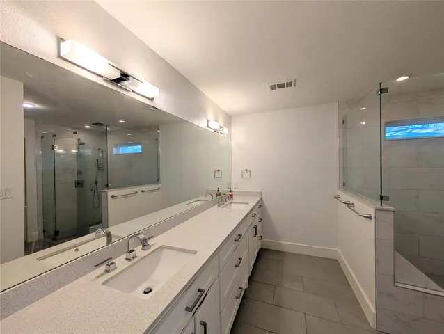 a spacious bathroom with a double vanity sink mirror and shower