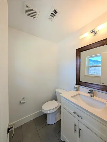 a bathroom with a granite countertop toilet a sink and mirror