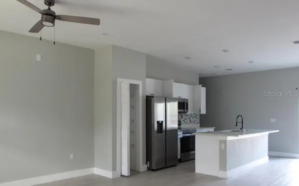 a large white room with stainless steel appliances a refrigerator and a fireplace