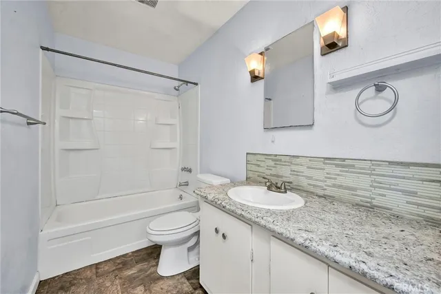 a bathroom with a granite countertop sink toilet and shower