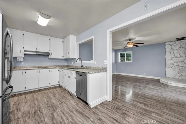 a kitchen with wooden floors and white cabinets