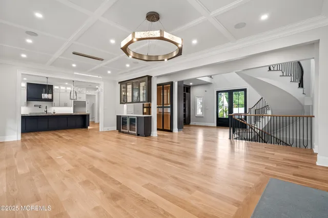 a view of an empty room and kitchen with furniture wooden floor and a ceiling fan