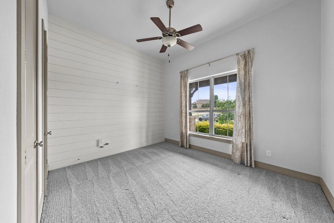8108 Turning Leaf Circle Lago Vista, TX 78645 - Photo 22 of 40 Light-filled bedroom with a shiplap feature wall and a peaceful view of the front landscaping.