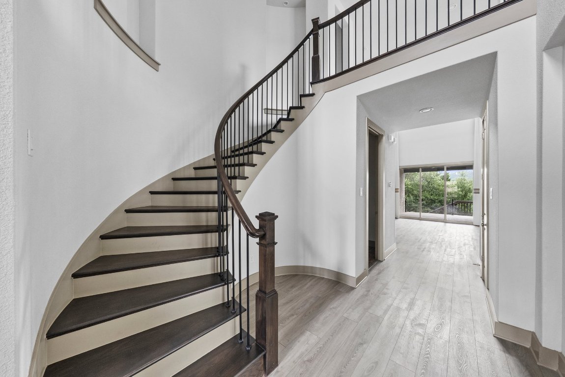 8108 Turning Leaf Circle Lago Vista, TX 78645 - Photo 24 of 40 A dramatic entrance featuring an elegant curved staircase and modern chandelier detail.