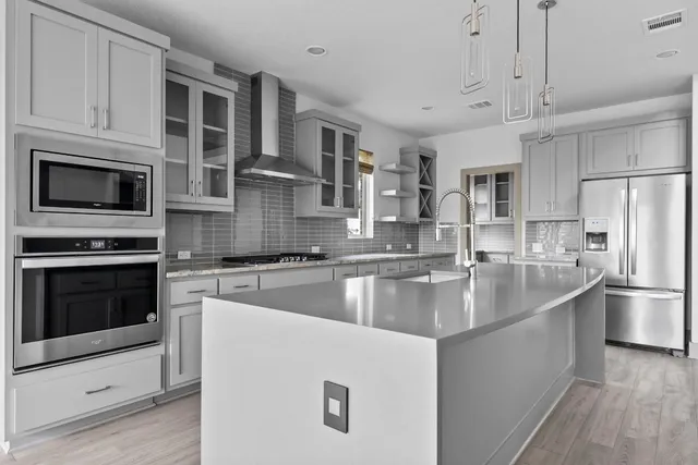 a kitchen with stainless steel appliances granite countertop a refrigerator a stove a microwave oven a sink dishwasher and white cabinets with wooden floor