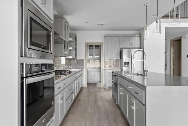 a kitchen with stainless steel appliances granite countertop a stove top oven a sink and dishwasher