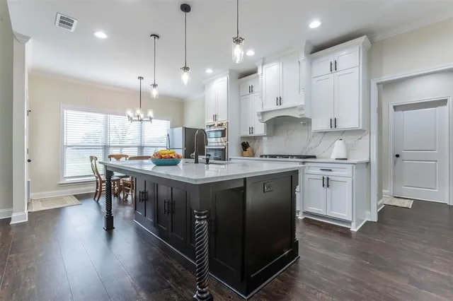 a kitchen with kitchen island granite countertop a stove a sink a center island and wooden floor