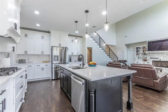 a kitchen that has a lot of cabinets a sink and wooden floor