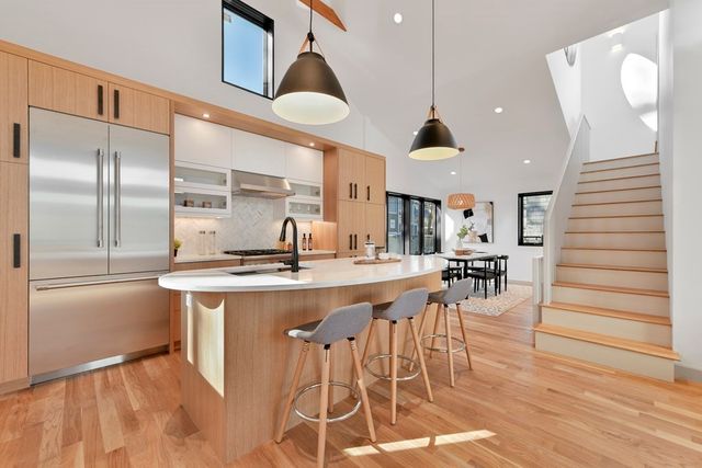 a kitchen with stainless steel appliances a dining table chairs and wooden floor