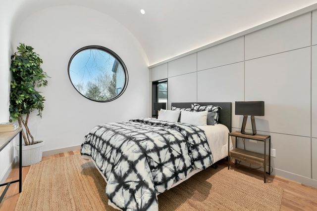 a bedroom with a bed and a potted plant next to a large window