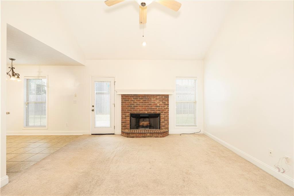 8 Ridgebrook Drive Phenix City, AL 36869 - Photo 8 of 21 Unfurnished living room with light colored carpet, light tile patterned flooring, a ceiling fan, a brick fireplace, and high vaulted ceiling