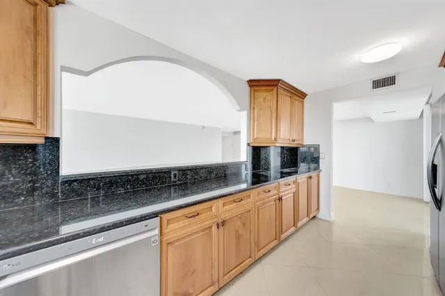 a kitchen with stainless steel appliances granite countertop a refrigerator a sink dishwasher and a stove