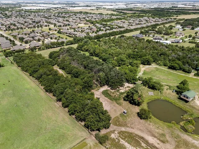 an aerial view of residential houses with outdoor space and trees
