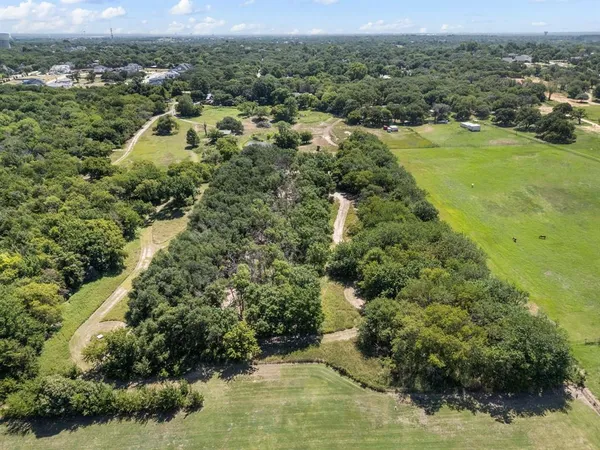 an aerial view of residential houses with outdoor space and trees