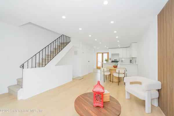 a living room with couches chairs and kitchen view with wooden floor