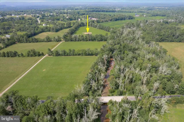 an aerial view of a residential houses with outdoor space and trees all around